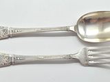 two silver spoons and a fork on a white surface
