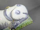 figurine en porcelaine représentant un panda allongé sur une surface verte