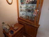 une armoire en bois avec une porte vitrée et une horloge accrochée au mur