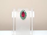 ruby and emerald leaf broochle on display in clear acrylic case