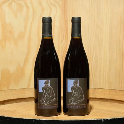 two bottles of wine sitting on top of a barrel