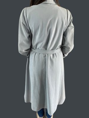 a woman in a gray coat is standing with her back to the camera