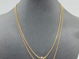 a gold necklace with two initials on a mannequin