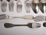 many spoons and forks laid out on the table