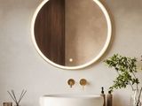 a white sink sitting under a round mirror on the wall