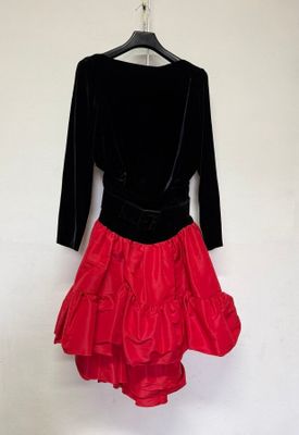 une robe rouge et noire suspendue à un cintre devant un mur blanc