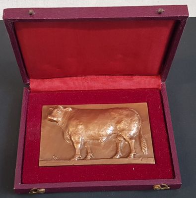 une vache en or dans une boîte rouge posée sur une table