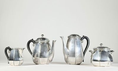 quatre théières en argent et une cafetière sur une table