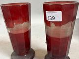 une paire de vases en verre rouge posés sur un comptoir blanc