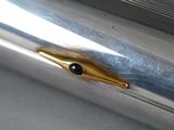 a metal pen with a gold tip and a black eye