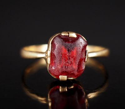 gros plan d'une bague en or avec une pierre rouge