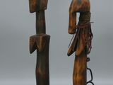 deux sculptures en bois représentant un homme et une femme, posées sur un socle