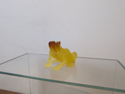 une petite grenouille jaune assise sur une table en verre
