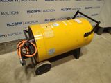 a large yellow barrel sitting on top of a cart in front of a wall