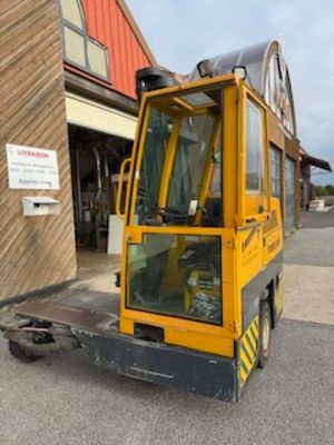 un chariot élévateur jaune garé devant un immeuble