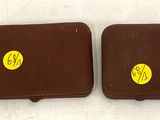 two brown leather cases with yellow stickers on them sitting on a white surface