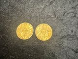 two gold coins sitting on top of a black surface