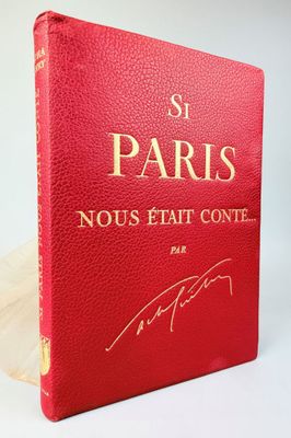 un livre rouge avec des lettres dorées posé sur une surface blanche