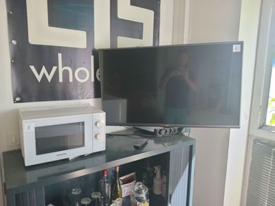 two televisions and a microwave sitting on top of a bookcase