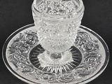 a close up of a glass cup and saucer on a plate