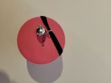 a pink box with a black ribbon and a ring on it