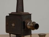 an old fashioned stove sitting on a table next to a cup