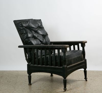 Large fauteuil en bois noirci. Assise en cuir noir capitonné…