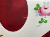 a close up of a red and white clock with a rose on it