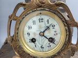 a clock that is sitting on a table with a statue on top of it