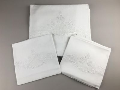 quatre serviettes blanches ornées de motifs brodés, posées sur une table