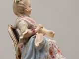 a figurine of a woman sitting on a chair