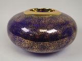 un vase violet bordé d'or posé sur une table blanche