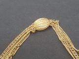 a close up of a gold chain bracelet with a coin on it