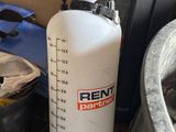 une bouteille d'eau blanche posée par terre à côté d'une poubelle
