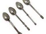 three silver spoons sitting on top of each other on a white surface