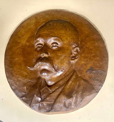 a bronze plaque of a man with a pipe in his mouth