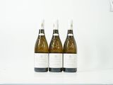 trois bouteilles de vin posées sur un plan de travail blanc