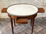 a small table with a marble top on a brick floor