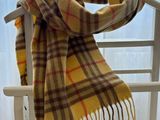 yellow and brown plaid scarf hanging on a clothes rack in front of a window