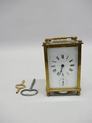 une petite horloge posée à côté d'une paire de ciseaux