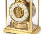 a gold clock with a face inside of a glass case