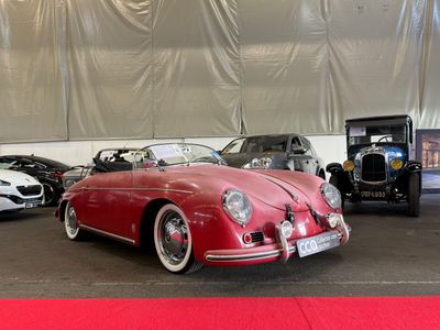 Plusieurs voitures de collection sont garées dans une grande salle recouverte d'un tapis rouge