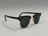 a pair of black sunglasses with gold trim and green lenses