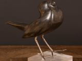sculpture of a bird on a marble base on a wooden table