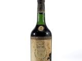 une vieille bouteille de vin posée sur une surface blanche