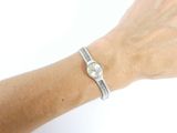 wrist shot of a woman wearing a silver bracelet with a watch on it