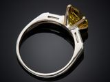 a close up of a ring with a yellow diamond on a black background