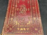 an old red book sitting on top of a black table