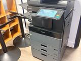 une imprimante multifonction posée sur un bureau, à côté d'une chaise