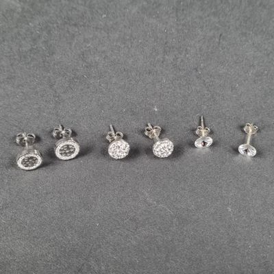 quatre paires de boucles d'oreilles en diamant posées sur une surface grise